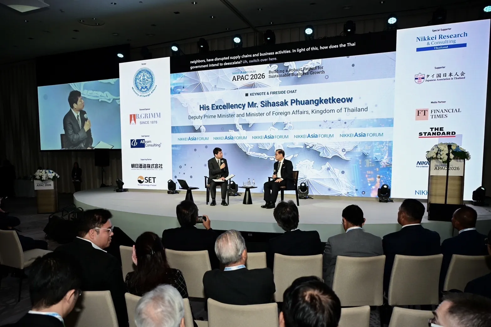 Fireside chat on the Nikkei Asia Forum APAC 2026 stage at Park Hyatt Bangkok, with TranSphere live translated captions displayed above the stage backdrop